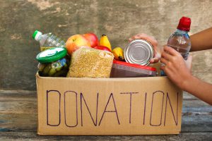 Cardboard box with the word Donation on it with food items in it.